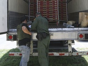 In this Aug. 13, 2017 photo, Border Patrol officers check the inside of a tractor-trailer in Edinburg, Texas. Police in Texas acting on a tip found the immigrants locked inside the tractor-trailer parked at a gas station about 20 miles (30 kilometers) from the border with Mexico, less than a month after 10 people died in the back of a hot truck with little ventilation in San Antonio. (Delcia Lopez/The Monitor via AP)