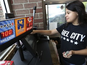Anahi Medrano sells a Powerball lottery ticket at a convenience store in Dallas Wednesday, Aug. 23, 2017. Lottery officials said the grand prize for Wednesday night's drawing has reached $700 million. The second -largest on record for any U.S. lottery game. (AP Photo/LM Otero)