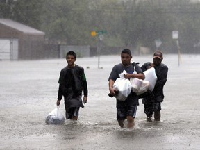 Jose Beltran, center, makes his was out of his neighborhood with his nephew Jonathan Beltran, left, and Abram Gutierrez as floodwaters from Tropical Storm Harvey continue to rise in Houston, Texas, Monday, Aug. 28, 2017. (AP Photo/LM Otero)