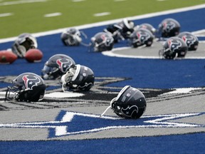 Several Houston Texans helmets sit over the Dallas Cowboys logo in the end zone as the Texans prepare for a morning work out at the Cowboys training facility, Monday, Aug. 28, 2017, in Frisco, Texas. The Texans are working out in the practice facility of the Cowboys because of floods pounding Houston. An exhibition game in the Texans' stadium Thursday might be moved to the home of the Cowboys.(AP Photo/Tony Gutierrez)