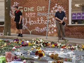 Jason Charter, left, of Washington, stands at a memorial, Wednesday, Aug. 16, 2017, in Charlottesville, Va., at the site where Heather Heyer was killed during a white nationalist rally. Charter was at the scene when a car rammed into a crowd of people protesting the rally. (AP Photo/Evan Vucci)