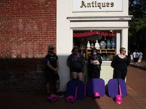 A group of people who chose not to be identified, stand with shields and bats near the site of a memorial service for Heather Heyer, who was killed during a white nationalist rally, Wednesday, Aug. 16, 2017, in Charlottesville, Va. The group is near the Paramount Theater in case white nationalist show up to protest the service. (AP Photo/Evan Vucci)