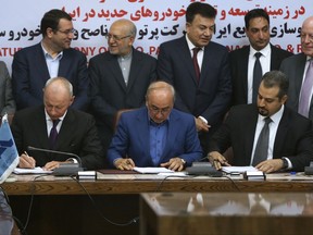 Chief Competitive Officer of Groupe Renault Thierry Bolloré, seated left, Chairman of Industrial Development and Renovation Oraganization of Iran, IDRO, Mansour Moazami, center, and Negin Group CEO Kourosh Morshed Solouk sign documents for a deal in Tehran, Iran, Monday, Aug. 7, 2017. Iran signed the country's biggest-ever car deal with French multinational automobile manufacturer Groupe Renault on Monday to produce 150,000 cars, beginning in 2018. (AP Photo/Vahid Salemi)