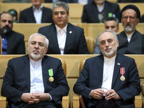 FILE-- In this file photo taken on Monday, Feb. 8, 2016, chief of Iran's Atomic Energy Organization Ali Akbar Salehi, right, sits next to Foreign Minister Mohammad Javad Zarif after being awarded medal of honor by President Hassan Rouhani during a ceremony in Tehran, Iran. Iran's atomic chief warned Tuesday the Islamic Republic needs only five days to ramp up its uranium enrichment to 20 percent, a level at which the material could be used for a nuclear weapon. (AP Photo/Ebrahim Noroozi, File)