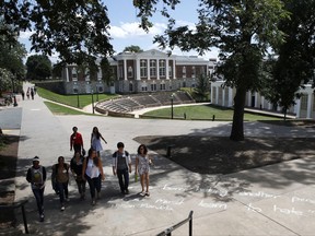 Students walks past a quote in chalk credited to Nelson Mandela at the University of Virginia, Friday, Aug. 18, 2017, in Charlottesville, Va., a week after a white nationalist rally took place on campus. The quote says "No one is born hating another person...people must learn to hate." (AP Photo/Jacquelyn Martin)