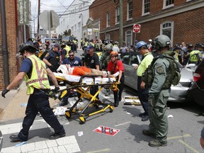 Rescue personnel help injured people after a car ran into a large group of protesters after a white nationalist rally in Charlottesville, Va., Saturday, Aug. 12, 2017.