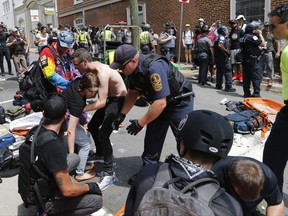 Rescue personnel help injured people after a car ran into a large group of protesters after a white nationalist rally in Charlottesville, Va., Saturday, Aug. 12, 2017.