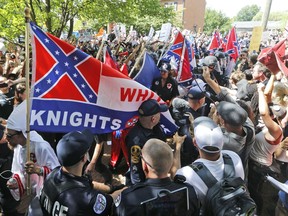 Members of the KKK escorted by police past a large group of protesters during a rally in Charlottesville, Va.