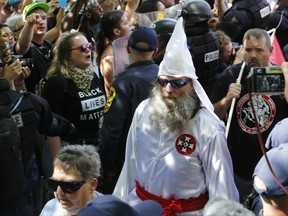 Members of the KKK escorted by police past a large group of protesters during a KKK rally in Charlottesville, Va.