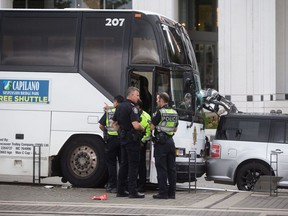 Police officers stand nearby after a collision involving a tour bus and pedestrians in Vancouver, B.C., on Sunday August 13, 2017. Four people were taken to hospital, two in critical condition and two with serious injuries according to the B.C. Ambulance Service. THE CANADIAN PRESS/Darryl Dyck