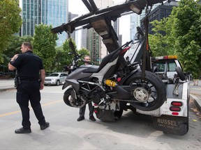 A police officer stands by as a tow truck operator removes a motorcycle from the scene after a female stunt driver working on the movie "Deadpool 2" died after a crash on set, in Vancouver, B.C., on Monday August 14, 2017. Vancouver police say the driver was on a motorcycle when the crash occurred on the movie set on Monday morning. THE CANADIAN PRESS/Darryl Dyck