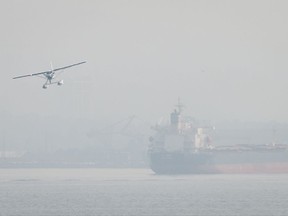 Smoke from wildfires burning in central British Columbia hangs in the air as a seaplane prepares to land on the harbour near the bulk carrier Nanakura, in Vancouver, B.C., on Thursday August 10, 2017. THE CANADIAN PRESS/Darryl Dyck