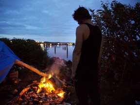 Alan, who is getting treated at a nearby methadone clinic while trying to kick his heroin addiction, stands by the fire outside his tent at the homeless encampment where he lives along the river in Aberdeen, Wash., Wednesday June 14, 2017. "I'm just trying to make it," said Alan who asked not to have his last name published and dreams of having his own RV some day. (AP Photo/David Goldman)