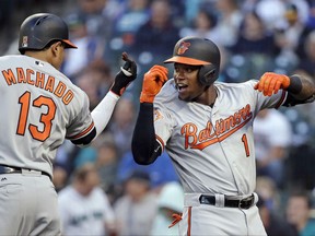 Baltimore Orioles' Tim Beckham (1) is congratulated by Manny Machado on his home run against the Seattle Mariners on the first pitch of the first inning of a baseball game, Monday, Aug. 14, 2017, in Seattle. (AP Photo/Elaine Thompson)