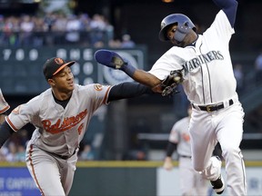 Baltimore Orioles second baseman Jonathan Schoop, center, reaches to tag out Seattle Mariners' Guillermo Heredia after Heredia was caught in a run-down while trying to steal second base in the first inning of a baseball game Tuesday, Aug. 15, 2017, in Seattle. (AP Photo/Elaine Thompson)
