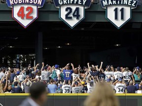 Former designated hitter Edgar Martinez, left, sits with his wife Holli Martinez as they watch the unveiling of his No. 11 during a ceremony retiring the number before a baseball game between the Mariners and Los Angeles Angels, Saturday, Aug. 12, 2017, in Seattle. (AP Photo/Elaine Thompson)