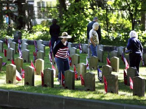 FILE - in this May 29, 2017 file photo, attendees peruse the grave markers in the Confederate Rest section after Memorial Day ceremonies at Forest Hill Cemetery in Madison, Wis.  Mayor Paul Soglin says monuments to confederate soldiers are being removed from the cemetery in traditionally liberal Madison, Wisconsin, because the Civil War was "a defense of the deplorable practice of slavery." Soglin made the announcement in a statement Thursday, Aug. 17.  (M.P. King/Wisconsin State Journal via AP)