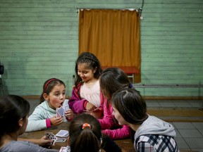 In this June 30, 2017 photo, transgender girl Selenna, left, plays cards during a break with other girls during a dance class at her community center in Santiago, Chile. Selenna's mother, Evelyn Silva, said she struggled to find a school that would accept a girl whose birth certificate still lists her as a boy, though she finally succeeded. (AP Photo/Esteban Felix)