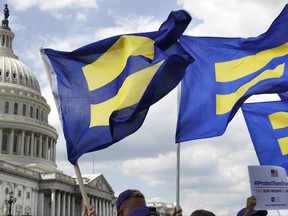 FILE - In this July 26, 2017 file photo, people with the Human Rights Campaign hold up "equality flags" during an event on Capitol Hill in Washington, in support of transgender members of the military. Officials say the Pentagon expects soon to ban transgender individuals from joining the military and to consider circumstances in which some currently serving transgender troops could remain in uniform.  (AP Photo/Jacquelyn Martin)