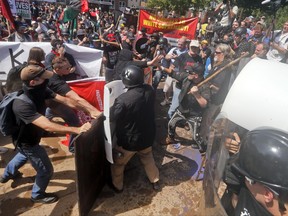 In this Saturday, Aug. 12, 2017, photo, white nationalist demonstrators clash with counter demonstrators at the entrance to Lee Park in Charlottesville, Va. President Donald Trump on Aug. 15, defended his response to Saturday's racially-charged protests in Charlottesville in a winding, combative exchange with reporters that at times mischaracterized the message and purpose of event. In his remarks, Trump described the rally as largely a debate over removal of a Confederate monument, although organizers billed the rally as push back against the "anti-white climate." Trump also misstated his levels of political support in the 2016 election. (AP Photo/Steve Helber)