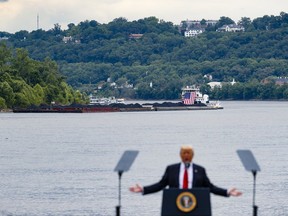 FILE - In this June 7, 2017 file photo, a coal barge is positioned as a backdrop behind President Donald Trump as he speaks during a rally at the Rivertowne Marina in Cincinnati. President Donald Trump personally promised to activate emergency legal authorities to keep dirty or economically uncompetitive coal plants from shutting down, a top American coal company said. The Trump administration now says it has no plans to do so.  (AP Photo/John Minchillo, File)