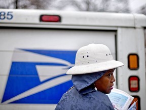 FILE - In this Feb. 7, 2014 file photo, U.S. Postal Service letter carrier Jamesa Euler delivers mail in the rain in Atlanta. Buffeted by threats from Amazon drones and Uber to delivery by golf cart, the beleaguered U.S. Postal Service is counting on a different strategy to stay ahead in the increasingly competitive package business: more freedom to raise your letter prices.  (AP Photo/David Goldman)