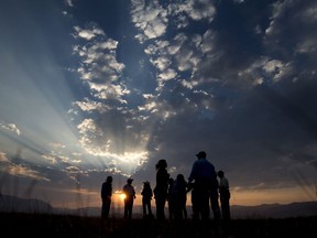 In this Monday, Aug. 28, 2017 photo, part of the group on hand to watch the release of 13 black-footed ferrets gather in the prairie dog colony enjoying the sunset during a release of 13 endangered black-footed ferrets on the historic Pitchfork Ranch near Meeteetse, Wyo. (Mark Davis/The Powell Tribune via AP)