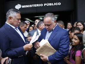 Venezuelan Constitutional assembly delegate and Leader of Venezuela's ruling socialist party Diosdado Cabello, center, and fellow delegate Pedro Carreno, left, leaf over their papers as they leave the General Prosecutors office in Caracas, Venezuela, Wednesday, Aug. 16, 2017. Cabello is alleging that the husband and close aides of ousted chief prosecutor Luisa Ortega ran a multi million dollar extortion ring. (AP Photo/Ariana Cubillos)