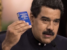 Venezuela's President Nicolas Maduro holds a copy of the constitution, as he speaks during a news conference in Caracas, Venezuela, Tuesday, Aug. 22, 2017. Immigration authorities in Colombia announced that Venezuela's ousted chief prosecutor Luisa Ortega Diaz is on her way to Brazil. Ortega said that Maduro removed her in order to stop a probe linking him and his inner circle to nearly $100 million in bribes from Brazilian construction company Odebrecht. (AP Photo/Ariana Cubillos)