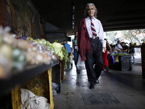 In this Aug. 23, 2017 photo, a man walks past vegetables for sale in Caracas, Venezuela. Authorities have started allowing companies to import items at the black market exchange rate, and letting them pass the dollar prices onto consumers, resulting in fuller shelves but with products out of reach for the vast majority of poor Venezuelans. (AP Photo/Ariana Cubillos)