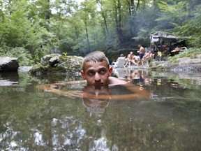 Bosnian man Adis Tokic cools off in a small creek near Tuzla, Bosnia, on Sunday, Aug. 6, 2017.  Hot weather has set in with temperatures rising up to around 40 Celsius across much of the region. (AP Photo/Amel Emric)