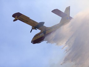 A firefighting plane drops its load on a wild fire approaching the village of Pucarica, near Abrantes, central Portugal, Friday, Aug.11, 2017. Strong winds and rising temperatures stoked wildfires in Portugal on Thursday, ending days of cooler weather that brought a brief respite from a spate of blazes, including one that killed 64 people in June. (AP Photo/Armando Franca)