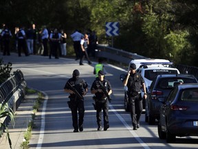 Armed policemen walk on a road near Subirats, Spain, during an operation Monday, Aug. 21, 2017. A police operation was underway Monday in an area west of Barcelona, and a Spanish newspaper reports that the fugitive in the city's van attack has been captured. Regional police said officers shot a man wearing a possible explosives belt in Subirats, a small town 45 kilometers (28 miles) west of Barcelona. (AP Photo/Emilio Morenatti)