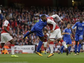 Arsenal's Alexandre Lacazette, centre heads the ball to score the opening goal of the game during their English Premier League soccer match between Arsenal and Leicester City at the Emirates stadium in London, Friday, Aug. 11, 2017. (AP Photo/Alastair Grant)