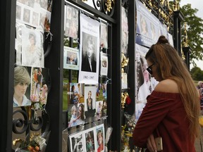 A woman looks at tributes and memorabilia for the late Diana, Princess of Wales outside Kensington Palace in London, Tuesday, Aug. 29, 2017. The tributes are placed on one of the ornamental gates at the palace ahead of the 20th anniversary of Princess Diana's death, in a car crash in Paris Aug. 31, 1997. (AP Photo/Alastair Grant)