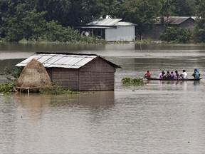 Flood affected people travel in a boat near partially submerged houses in Morigaon district east of Gauhati, Assam, India, Tuesday, Aug. 15, 2017. Heavy monsoon rains have unleashed landslides and floods that killed dozens of people in recent days and displaced millions more across northern India, southern Nepal and Bangladesh. (AP Photo/Anupam Nath)