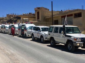 This Monday, July 31, 2017 photo released by the government-controlled Syrian Central Military Media, shows ambulances of the Syrian Arab Red Crescent gathering in the Syrian border village of Fleeta. The government-controlled Syrian Central Military Media released videos and photos of buses and ambulances near the Lebanese border town of Arsal and the Syrian village of Fleeta preparing for the evacuations. The second round of an exchange between Lebanon's militant Hezbollah group and Syria's al-Qaida affiliate that would lead to thousands of refugees resettled in Syria. (Syrian Central Military Media, via AP)