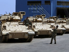 Lebanese army soldiers take pictures near military vehicles that were unloaded from a ship at Beirut's port in Lebanon, Monday, Aug. 14, 2017. The United State handed over the Lebanese army eight Bradley Fighting Vehicles part of 32 that will be delivered in the coming months. The U.S. has supplied the military with helicopters, anti-tank missiles, artillery and radars, as well as training. (AP Photo/Bilal Hussein)