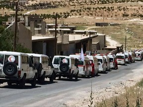 This Monday, July 31, 2017 photo released by the government-controlled Syrian Central Military Media, shows ambulances of the Syrian Arab Red Crescent gathering in the Syrian border village of Fleeta. The government-controlled Syrian Central Military Media released videos and photos of buses and ambulances near the Lebanese border town of Arsal and the Syrian village of Fleeta preparing for the evacuations. The second round of an exchange between Lebanon's militant Hezbollah group and Syria's al-Qaida affiliate that would lead to thousands of refugees resettled in Syria. (Syrian Central Military Media, via AP)