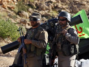 This Saturday, July 29, 2017 photo, Hezbollah fighters stand on their army vehicle at the site where clashes erupted between Hezbollah and al-Qaida-linked fighters in Wadi al-Kheil or al-Kheil Valley in the Lebanon-Syria border. When President Trump praised the Lebanese government for fighting Hezbollah last week, the Iranian-backed group was busy demonstrating just how wrong he was, clearing the country's eastern frontier from al-Qaida and negotiating a complex prisoners swap with the militant group alongside the Lebanese government. (AP Photo/Bilal Hussein)