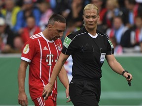 FILE - In this Aug. 12, 2017 file photo Munich's Franck Ribery and referee Bibiana Steinhaus walk on the pitch during the German Soccer Cup first-round soccer match between Chemnitzer FC and FC Bayern Munich in Chemnitz, Germany. Carving her way in a man's world, Bibiana Steinhaus is striking a blow for equality as the Bundesliga's first female referee this season. The 38-year-old police officer, who has been refereeing in the second division since 2007, is one of four referees promoted by the German football federation (DFB) to the top flight.  (Hendrik Schmidt/dpa via AP,file)