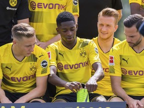 File - In this Aug. 9, 2017 file photo Dortmund's  Ousmane Dembele, second left, sits next to Felix Passlack, left, Marco Reus  and Dortmund's s Gonzalo Castro, right,  during a team photo call in Dortmund, Germany. Borussia Dortmund will have their first match of the new season vs VfL Wolfsburg in Wolfsburg  on Saturday, Aug. 19, 2017.  (Guido Kirchner/dpa via AP,file)