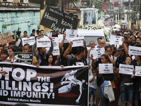 Protesters and supporters carry banners and placards as they march with the hearse of slain Kian Loyd delos Santos, a 17-year-old student, during his funeral Saturday, Aug. 26, 2017, in suburban Caloocan city north of Manila, Philippines. The killing of Kian has sparked an outcry against President Rodrigo Duterte's anti-drug crackdown, which has left thousands dead since assuming office in June of last year. (AP Photo/Bullit Marquez)