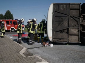 Firefighters and rescuers stand near the debris of a bus that crashed in  Bohmte, near Osnabrueck, northern Germany, Wednesday, Aug. 23, 2017.  Police say 44 people, most of them women from Romania, have been injured in a bus accident in northern Germany. Police spokeswoman Anke Hamker said the driver was on a country road near the city of Osnabrueck on Wednesday, when he lost control over his vehicle because of technical problems and the bus then fell on its side.  (Nord-West-Media TV/dpa via AP)