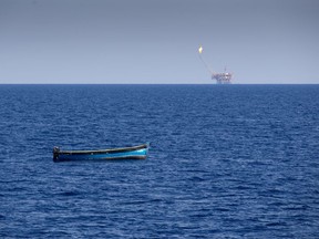 Backdropped by an oil rig, an abandoned wooden boat floats in the Mediterranean Sea north of the Libyan coast, Tuesday, Aug. 29, 2017. Rescuers from the Aquarius vessel of SOS Mediterranee and MSF (Doctors Without Borders) NGOs rescued seven persons from the boat which departed Libya the previous night. (AP Photo/Darko Bandic)
