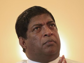 FILE- In this May 25, 2017 file photo, Sri Lanka's then appointed foreign minister Ravi Karunanayake prays during a function to invoke blessings, as is customary practice before the start of important activities, as he assumes office in Colombo, Sri Lanka. Karunanayake resigned on Thursday Aug. 10, 2017 after being accused of possessing a luxury apartment paid for by a businessman investigated for shady treasury bond transactions. (AP Photo/Eranga Jayawardena, File)