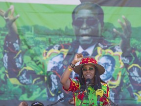 FILE -- In this Friday, July 21, 2017 file photo Zimbabwe's first lady, Grace Mugabe, greets supporters at a rally in Lupane, Zimbabwe. South Africa's police minister says the wife of Zimbabwe's president, background image, has handed herself over to police after being accused of assaulting a young woman Sunday night. (AP Photo/Tsvangirayi Mukwazhi, File)