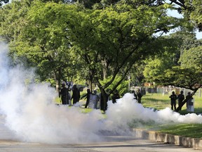 Venezuelan Bolivarian National Guard officers fire teargas toward a resident who tries to walk to the Paramacay military base in Valencia, Venezuela, Sunday Aug. 6, 2017. Venezuelan ruling party chief Diosdado Cabello said the military squashed a "terrorist" attack at the military base Sunday, shortly after a small group of men dressed in military fatigues released a video declaring themselves in rebellion. (AP Photo/Juan Carlos Hernandez)