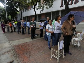 Voters wait outside of a poll station to enter to cast their ballots during the election for a constitutional assembly in Caracas, Venezuela, Sunday, July 30, 2017. President Nicolas Maduro asked for global acceptance on Sunday as he cast an unusual pre-dawn vote for an all-powerful constitutional assembly that his opponents fear he'll use to replace Venezuelan democracy with a single-party authoritarian system. (AP Photo/Ariana Cubillos)
