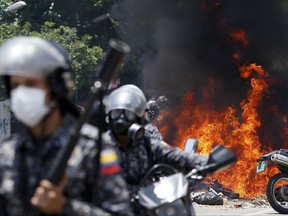 Venezuelan Bolivarian National police move away from the flames after an explosion at Altamira square during clashes against anti-government demonstrators in Caracas, Venezuela, Sunday, July 30, 2017.